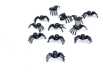 May include: A collection of twelve black plastic toy spiders on a white background.