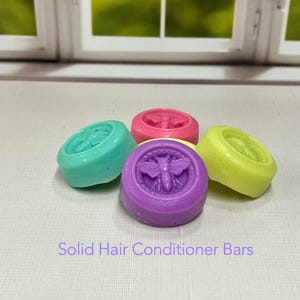May include: A collection of colorful solid hair conditioner bars in shades of teal, pink, purple, and yellow. Each bar features a raised butterfly design. The text "Solid Hair Conditioner Bars" is visible.
