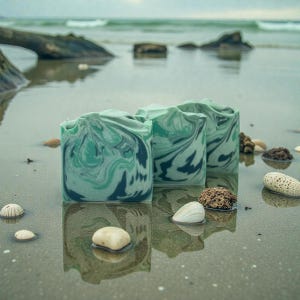 May include: Three rectangular bars of soap featuring a marbled pattern in shades of sage green, dark teal, and white. The soap bars have a smooth, slightly uneven top edge and are arranged in a cluster, displaying a swirling color design.