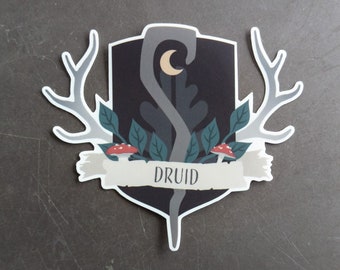 May include: A black and white sticker with a crest featuring a crescent moon, antlers, leaves, and mushrooms. The crest is surrounded by a white banner with the word "DRUID" printed in black.