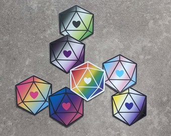 Puede incluir: Conjunto de siete pegatinas de dados de colores con un diseño de corazón. Cada dado es de un color diferente y tiene un corazón en el centro. Los dados están dispuestos en círculo.