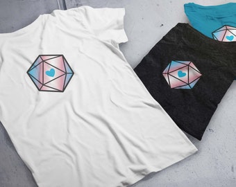Puede incluir: Tres camisetas con un gráfico de una bandera del orgullo transgénero dentro de un dado en forma de corazón. Las camisetas son blancas, negras y azul verdoso.