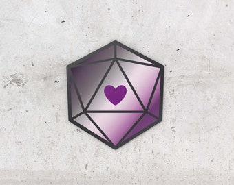 Puede incluir: Un dado de 20 caras con un degradado de color púrpura y blanco y un corazón púrpura en el centro. El dado es un accesorio de juego popular.