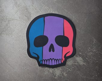 Puede incluir: Una pegatina de calavera en blanco y negro con un diseño de rayas moradas, azules y rojas.