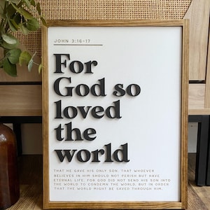 May include: A white framed wood sign with black lettering that reads "For God so loved the world" and the Bible verse John 3:16-17. The sign has a rustic wood frame.