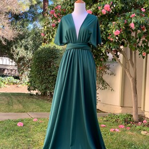 May include: A deep green maxi dress with a plunging V-neckline and short, wide sleeves. The dress has a wrap-style bodice and a flowing skirt.