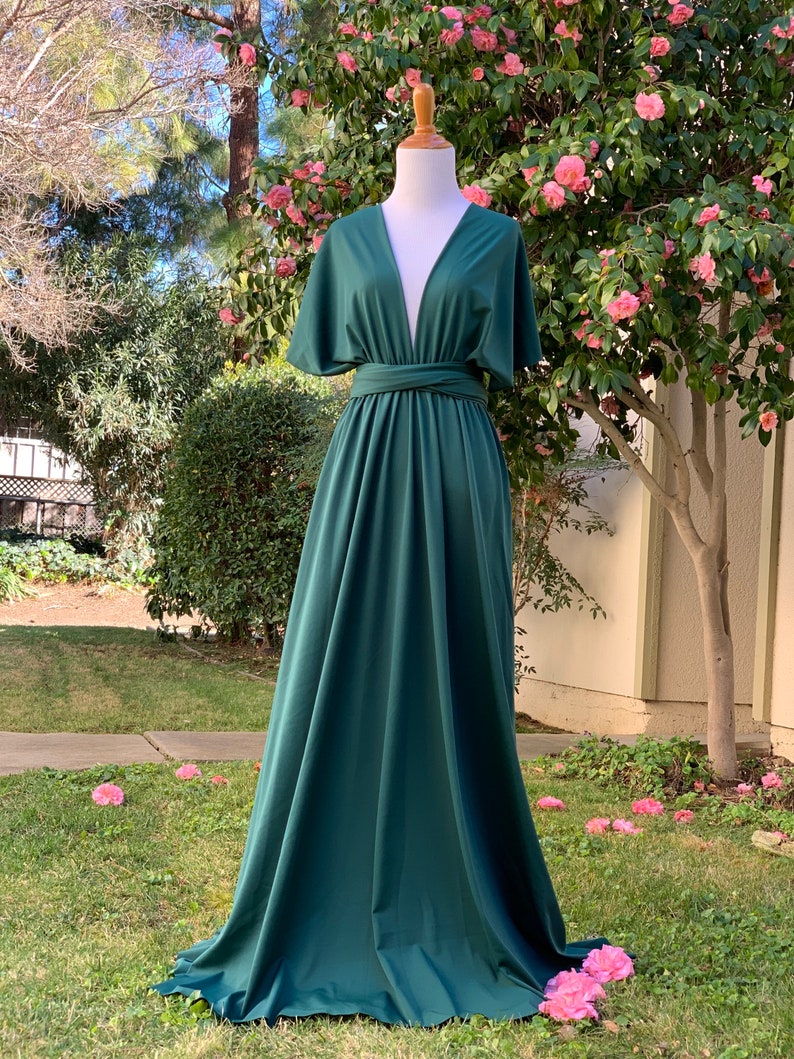 May include: A deep green maxi dress with a plunging V-neckline and short, wide sleeves. The dress has a wrap-style bodice and a flowing skirt.