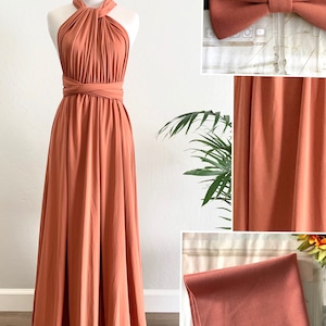 Op de afbeelding: Een terracotta maxi-jurk met een halternek en een wikkel-bovenstuk. De jurk is gemaakt van een zachte, rekbare stof en heeft een zwierige rok. De stof wordt op een aparte afbeelding getoond.