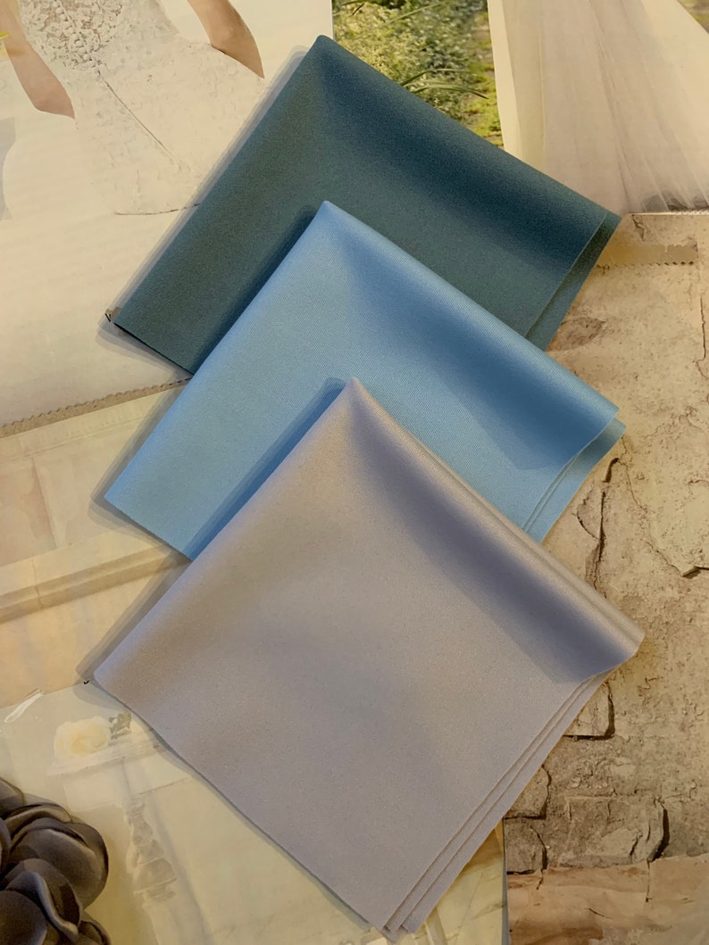 Op de afbeelding: Drie stofstalen in verschillende tinten blauw. De stalen zijn in een driehoekige vorm gerangschikt, met de donkerste blauwe tint bovenaan en de lichtste blauwe tint onderaan.