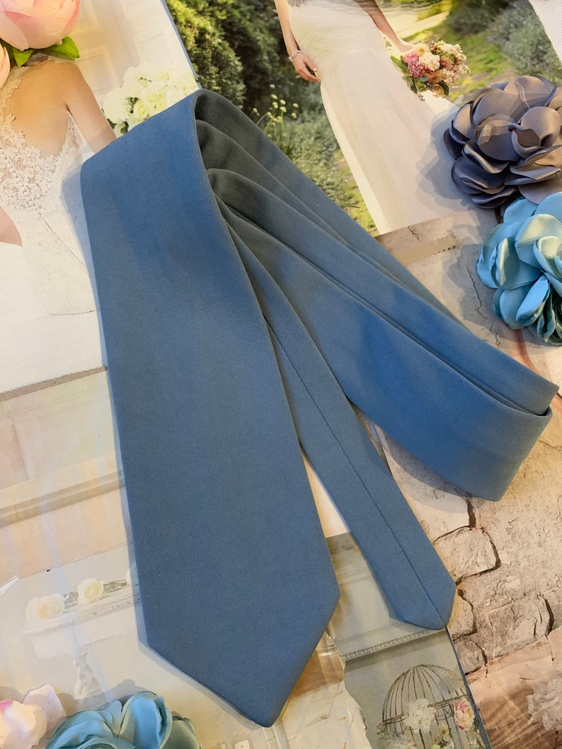 Op de afbeelding: Een effen blauwe stropdas met een puntig uiteinde. De stropdas is gemaakt van gladde stof en heeft een subtiele glans.