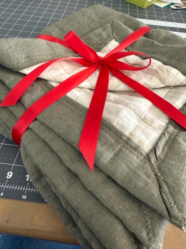 May include: Stack of five olive green linen dish towels tied with a red ribbon.