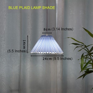 May include: Blue and white plaid lampshade with a pleated design. The shade is 9.5 inches wide and 5.5 inches tall.