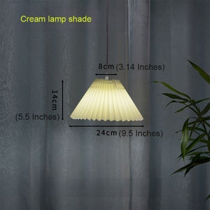 May include: Cream colored pleated lampshade with a diameter of 9.5 inches and a height of 5.5 inches.