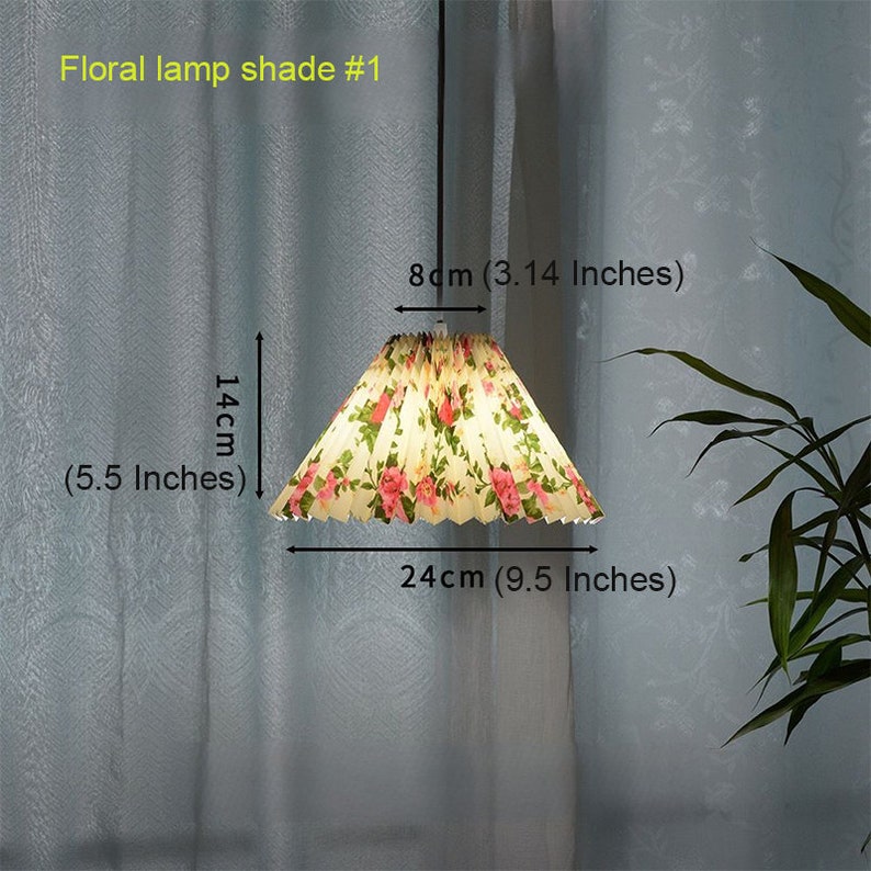 May include: A floral lamp shade with a white background and pink flowers. The shade is 9.5 inches wide and 5.5 inches tall.