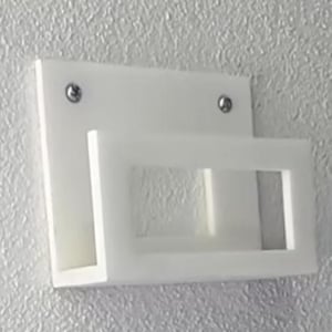 May include: A white, wall-mounted shelf with a rectangular backplate and a projecting, open-fronted shelf. Two silver screws secure the shelf to the wall. The shelf is made of a solid, opaque material.