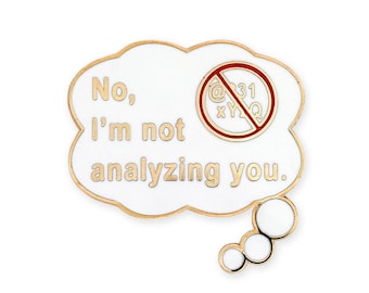 May include: Gold-coloured enamel pin with a white cloud shape. The cloud has a speech bubble with the text "No, I'm not analysing you." and a red circle with a diagonal line through it. The circle contains the text "@31 xyZQ".