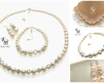 May include: A bridal jewelry set featuring a necklace, bracelet, and earrings. The set includes faux pearls and sparkling crystal accents. The necklace and bracelet have alternating pearl and crystal clusters. The earrings are pearl drops with crystal accents. The logo "KB By Ky's Bridal" is visible.