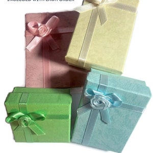May include: Four small gift boxes in pastel colors: pink, yellow, green, and blue. Each box is rectangular and tied with a matching ribbon and a decorative rose. The boxes are arranged on a white background.