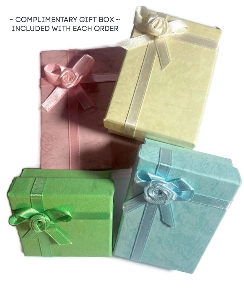 May include: Four small gift boxes in pastel colors: pink, yellow, green, and blue. Each box is rectangular and tied with a matching ribbon and a decorative rose. The boxes are arranged on a white background.