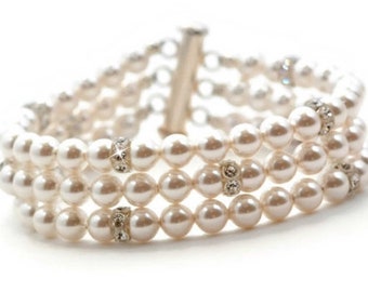 May include: Elegant three-strand pearl bracelet with silver-tone accents. Each strand features lustrous, creamy-white pearls. Sparkling rhinestone embellishments add a touch of glamour. The bracelet is secured with a silver clasp.