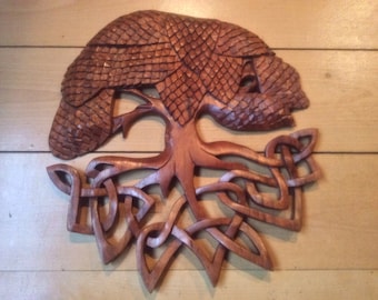 May include: A wooden carving of a tree with intricate roots and a Celtic knot design. The tree is brown and the roots are intertwined.