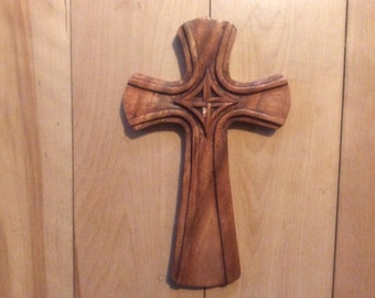 Könnte beinhalten: Ein Holzkreuz mit einem geschnitzten keltischen Knotendesign. Das Kreuz ist dunkelbraun und hat eine glatte, polierte Oberfläche.
