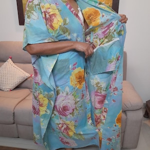 May include: A light blue floral print kaftan with a long, flowing design. The kaftan has a V-neck and short sleeves. The fabric is soft and comfortable.