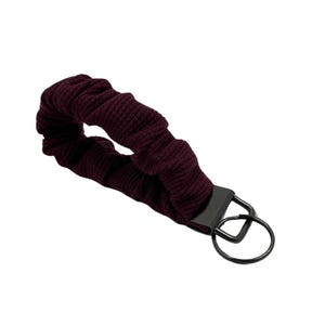 May include: A burgundy fabric key chain with a black metal key ring.