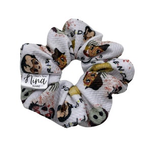 May include: White scrunchie with a repeating pattern of characters from the TV show "Friends" and the text "Friends". The scrunchie has a white label with the text "That's Sew Nina Marie".