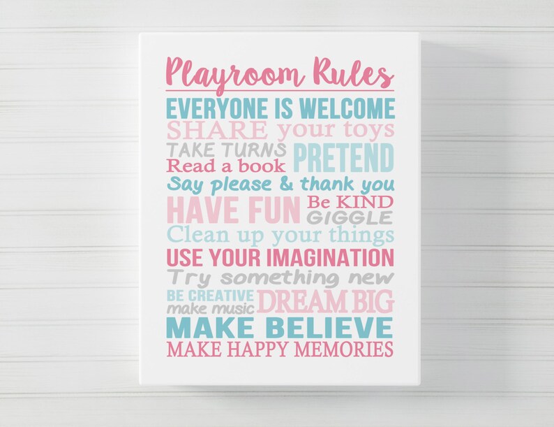 May include: A white sign with pink and blue text that reads "Playroom Rules" and lists rules for children, such as "Share your toys", "Take turns", "Pretend", "Read a book", "Say please & thank you", "Have fun", "Be kind", "Giggle", "Clean up your things", "Use your imagination", "Try something new", "Be creative", "Dream big", "Make music", "Make believe", and "Make happy memories".