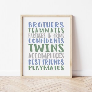 May include: A framed print with the words "Brothers, Teammates, Partners in Crime, Confidants, Twins, Accomplices, Best Friends, Playmates" in blue and green lettering on a white background.
