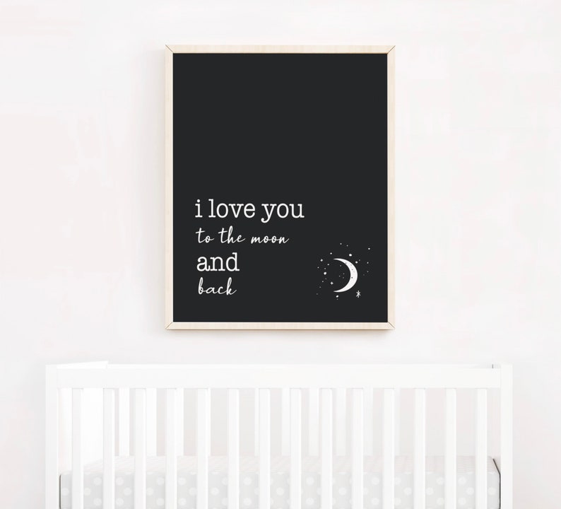 Op de afbeelding: Een zwart-wit print met de tekst "i love you to the moon and back". De print toont een illustratie van een maan en sterren. Het kunstwerk wordt boven een witte wieg getoond.