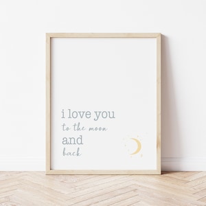 Op de afbeelding: Een ingelijste print met de tekst "i love you to the moon and back" in grijze letters. Een gele halve maan en steraccenten bevinden zich in de rechter benedenhoek. De lijst is van licht hout en de achtergrond is wit.