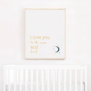 Op de afbeelding: Een ingelijste print met de woorden "i love you to the moon and back" in gouden letters. Een donkerblauwe halve maan en sterrenafbeelding staat rechts. De print hangt boven een witte wieg.