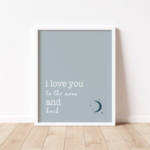 Op de afbeelding: Een ingelijste print met een lichtblauwe achtergrond en witte tekst met de tekst "i love you to the moon and back". Een halve maan en sterren staan in de rechter benedenhoek. De lijst is wit.