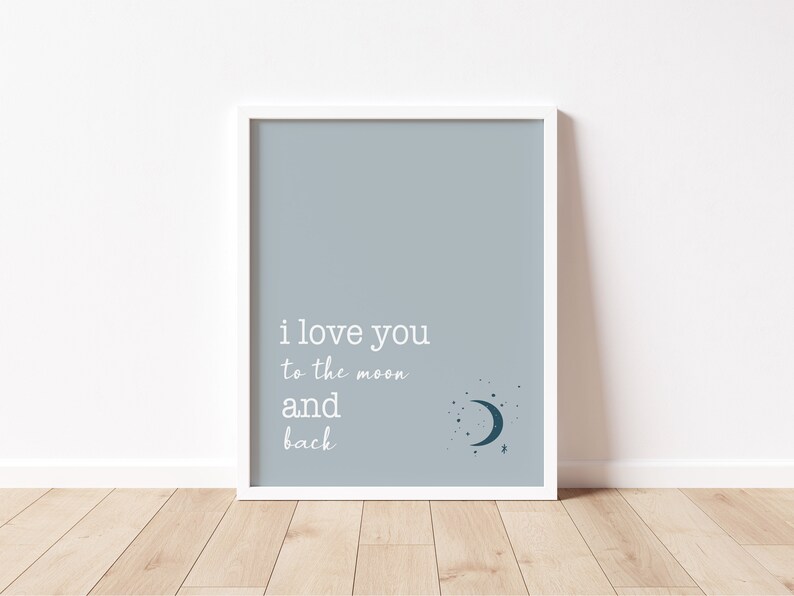 Op de afbeelding: Een ingelijste print met een lichtblauwe achtergrond en witte tekst met de tekst "i love you to the moon and back". Een halve maan en sterren staan in de rechter benedenhoek. De lijst is wit.