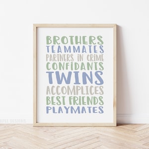 May include: A framed print with the text "Brothers, Teammates, Partners in Crime, Confidants, Twins, Accomplices, Best Friends, Playmates" in blue and green lettering on a white background.