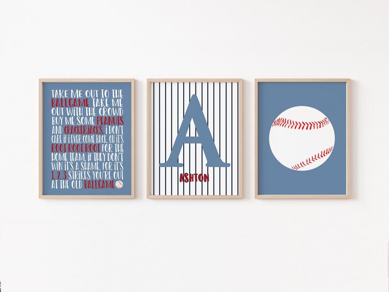 Może przedstawiać: Trzy wydruki w stylu baseballowym do pokoju dziecięcego lub pokoju niemowlęcia. Pierwszy wydruk zawiera tekst piosenki "Take Me Out to the Ballgame". Drugi wydruk przedstawia niebieską literę "A" na biało-niebieskim paskowanym tle z napisem "Ashton" poniżej. Trzeci wydruk przedstawia białą piłkę baseballową z czerwonymi szwami na niebieskim tle.