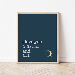 Op de afbeelding: Ingelijste kunstdruk met een marineblauwe achtergrond en de witte tekst "i love you to the moon and back". Een gouden halve maan en sterren staan in de rechter benedenhoek. De lijst heeft een lichte houtkleur.