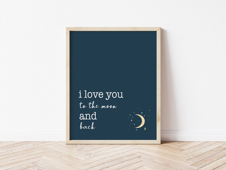 Op de afbeelding: Ingelijste kunstdruk met een marineblauwe achtergrond en de witte tekst "i love you to the moon and back". Een gouden halve maan en sterren staan in de rechter benedenhoek. De lijst heeft een lichte houtkleur.