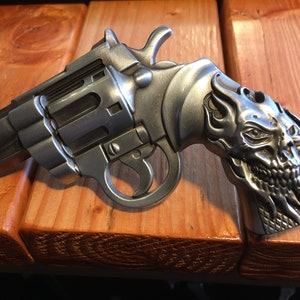 May include: A silver revolver with a skull and flames design on the handle.