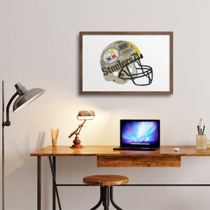 May include: A framed print of a Pittsburgh Steelers football helmet made from newspaper clippings. The helmet is yellow and black with the team's logo and the word "Steelers" printed on it.