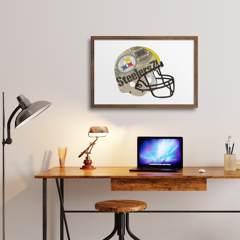 May include: A framed print of a Pittsburgh Steelers football helmet made from newspaper clippings. The helmet is yellow and black with the team's logo and the word "Steelers" printed on it.