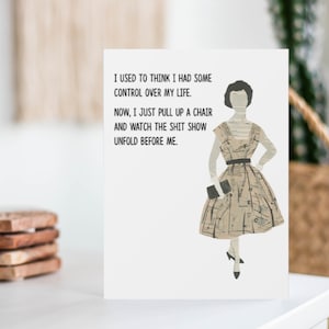 Peut inclure: Une carte blanche avec une illustration en noir et blanc d'une femme en robe. Le texte sur la carte dit : "Je pensais avoir un certain contr&ocirc;le sur ma vie. Maintenant, je me contente de tirer une chaise et de regarder le spectacle se d&eacute;rouler devant moi."