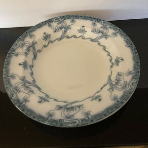 May include: A white ceramic plate with a blue and white floral design. The plate has a scalloped edge and a raised rim.