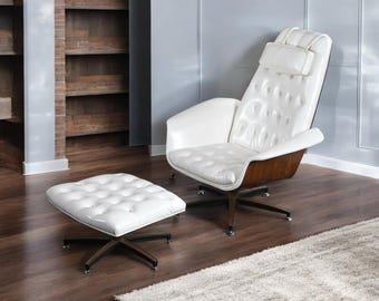 May include: A white leather armchair and matching ottoman set. The chair has a high back with a headrest and button tufting. The base is a dark wood with a star-shaped metal base. The ottoman has a similar design.
