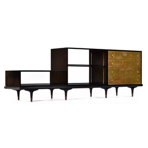 May include: A black wooden entertainment center with a shelf unit and a cabinet with four drawers. The cabinet doors are made of wood with a gold leaf finish and have decorative brass pulls.