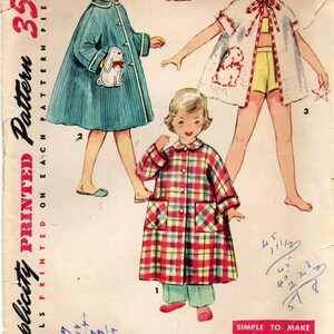 Op de afbeelding: Vintage Simplicity patroon 4503, maat 5. De afbeelding toont drie kinderkleding: een blauwe badjas met een konijn applicatie, een witte badjas met rode bies en een konijn applicatie, en een geruite badjas. Het patroon is gemarkeerd met "Simple to Make".