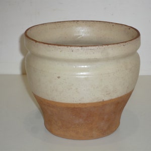 Peut inclure: Un pot en céramique blanche avec une base en terre cuite brune. Le pot a une forme arrondie et un bord légèrement évasé.