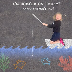 Puede incluir: Una niña vestida con una camisa negra y una falda azul está fingiendo pescar con una caña de pescar blanca dibujada en el suelo. Las palabras "I'm hooked on Daddy! Happy Father's Day!" están escritas con tiza blanca sobre el asfalto negro. La niña está de pie en un barco de tiza blanca con olas azules dibujadas a su alrededor. Hay dos peces y un arrecife de coral dibujados en el suelo.